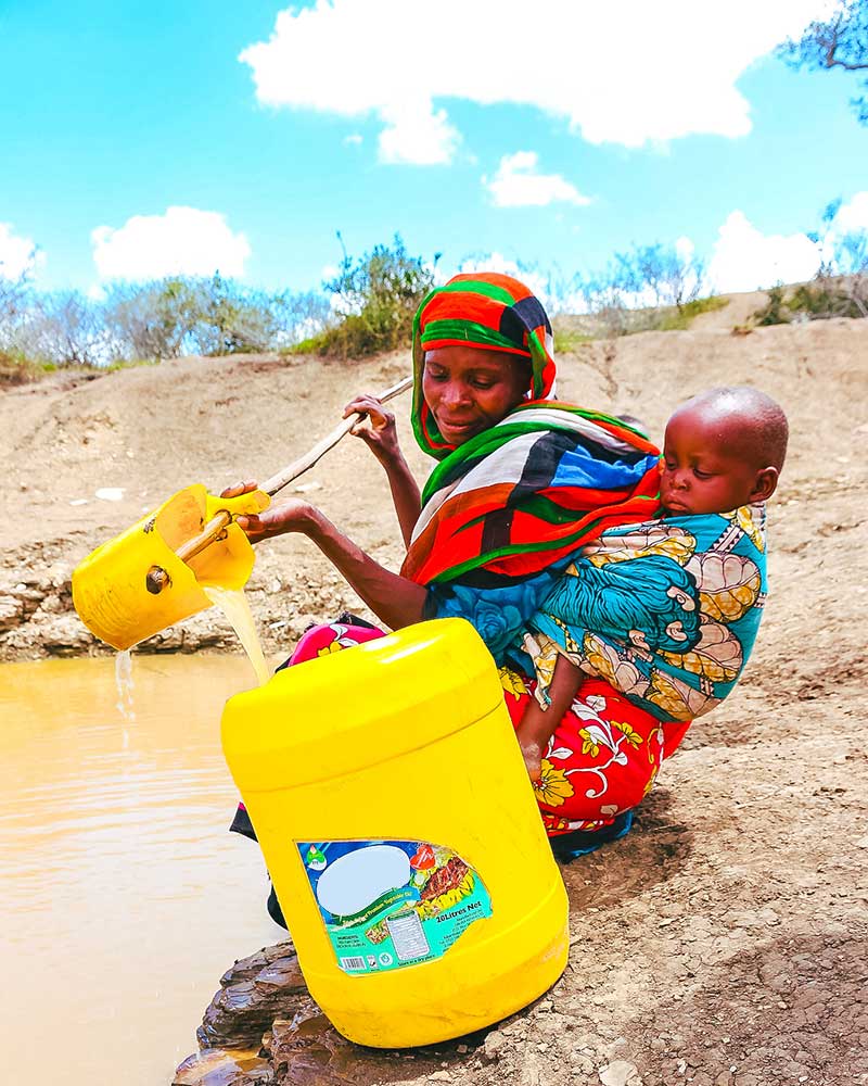 Lady collecting dirty water. The Stream Project